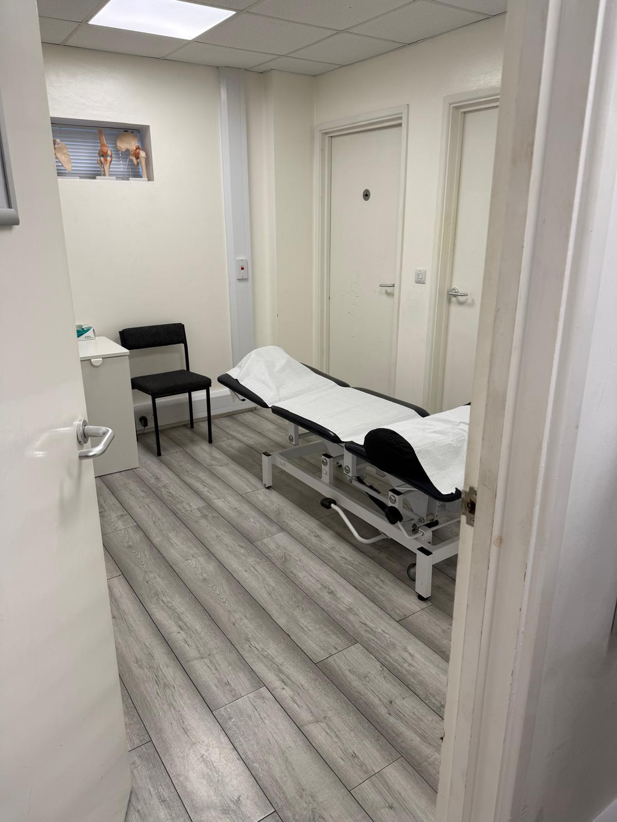 Clinical examination room at PC Physiotherapy Newport Pagnell — adjustable treatment bed and clinical seating for private GP and specialist appointments